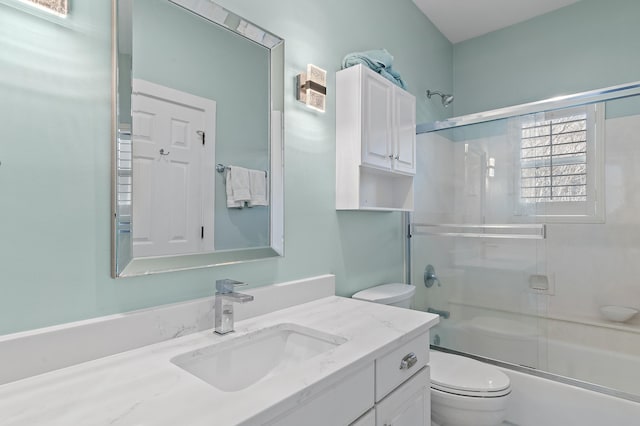 bathroom featuring enclosed tub / shower combo, vanity, and toilet