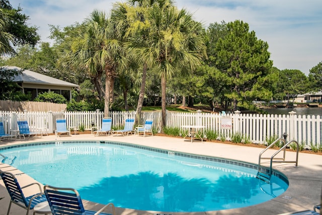 community pool with a patio area and fence