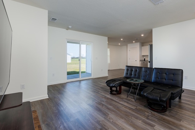 sitting room with dark wood-type flooring, visible vents, and a textured ceiling