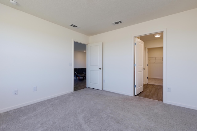 unfurnished bedroom with carpet, visible vents, and a textured ceiling