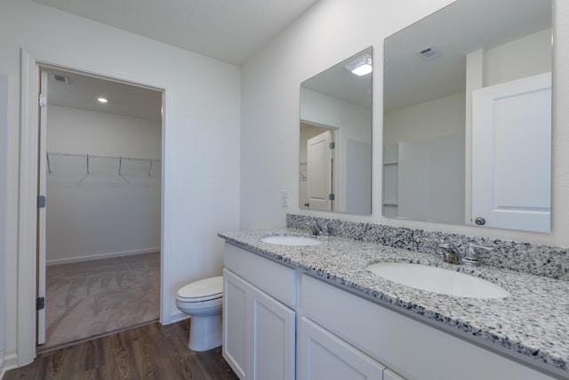 full bath featuring wood finished floors, a sink, visible vents, and a walk in closet