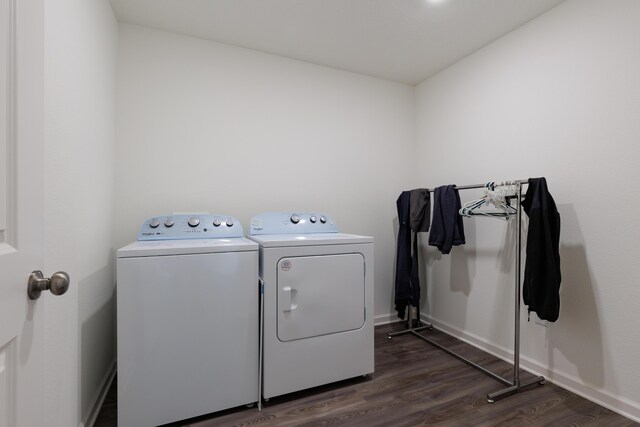 clothes washing area with dark wood-type flooring, laundry area, washer and clothes dryer, and baseboards