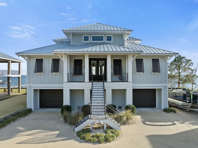 view of front of house featuring board and batten siding, metal roof, driveway, and stairs