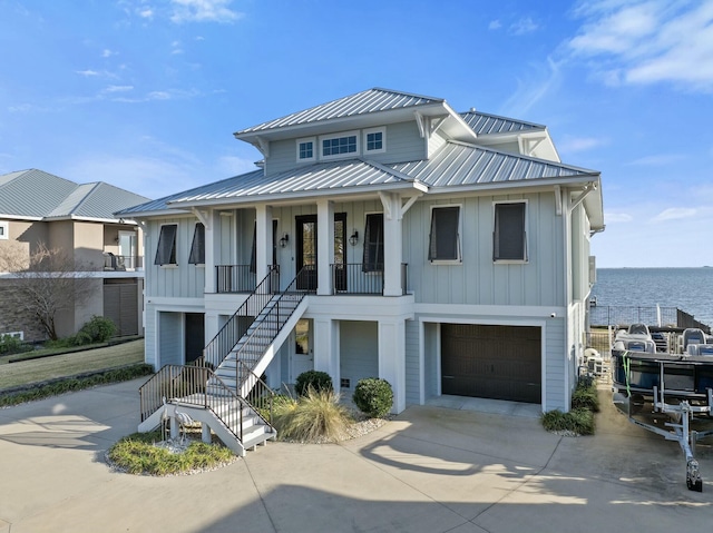 view of front facade featuring a porch, concrete driveway, board and batten siding, metal roof, and stairs