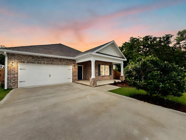 view of front facade with brick siding, a shingled roof, covered porch, concrete driveway, and an attached garage