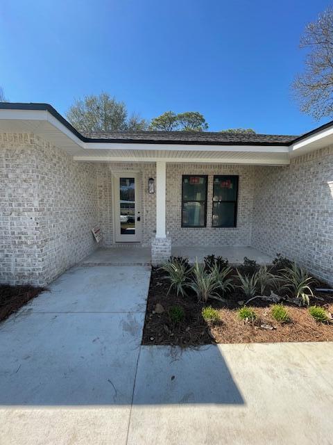 entrance to property with a porch and brick siding