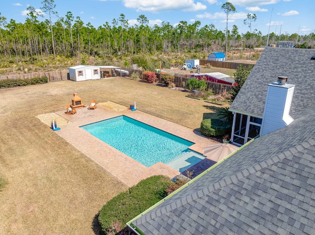 view of pool featuring an outbuilding, a yard, a storage unit, and a fenced backyard