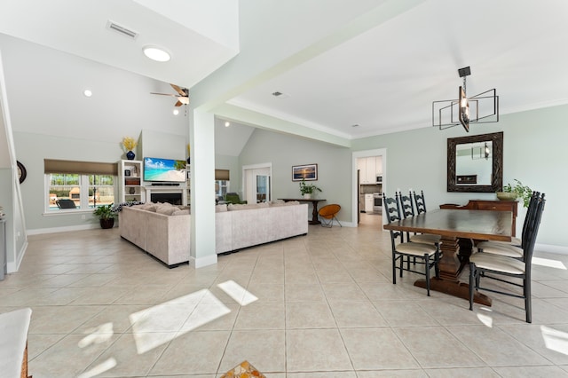 living area with a fireplace, light tile patterned flooring, vaulted ceiling, baseboards, and ceiling fan with notable chandelier