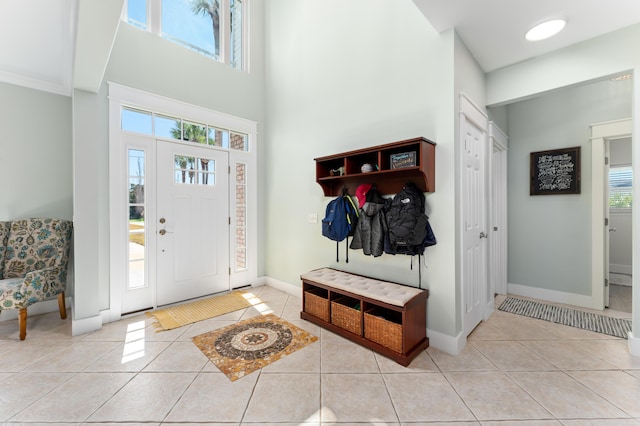 tiled foyer entrance with a towering ceiling and baseboards