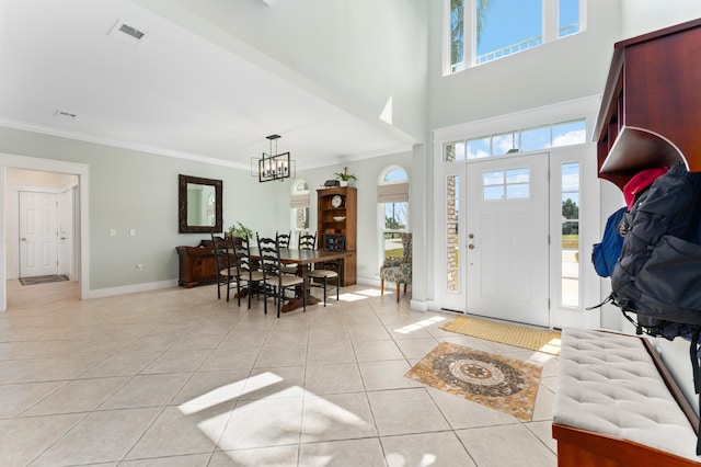 foyer entrance featuring light tile patterned floors, ornamental molding, a chandelier, and a wealth of natural light