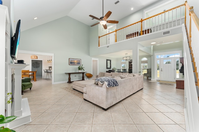 living area with ceiling fan with notable chandelier, visible vents, baseboards, and light tile patterned floors