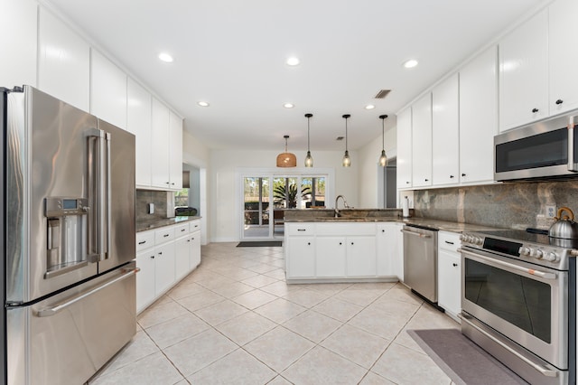 kitchen with a peninsula, stainless steel appliances, a sink, and light tile patterned flooring