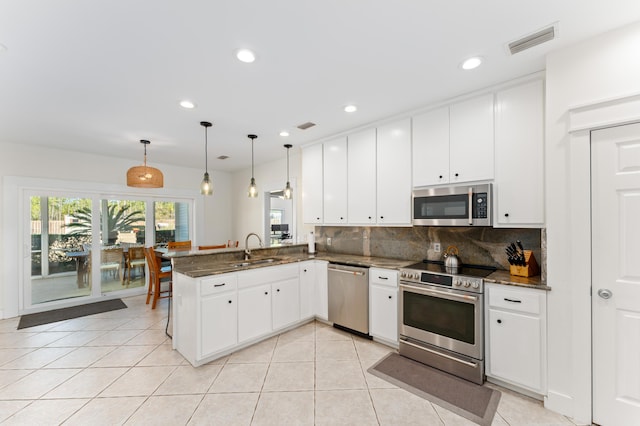 kitchen featuring stainless steel appliances, visible vents, decorative backsplash, a sink, and a peninsula