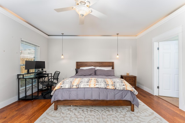 bedroom featuring a ceiling fan, crown molding, baseboards, and wood finished floors