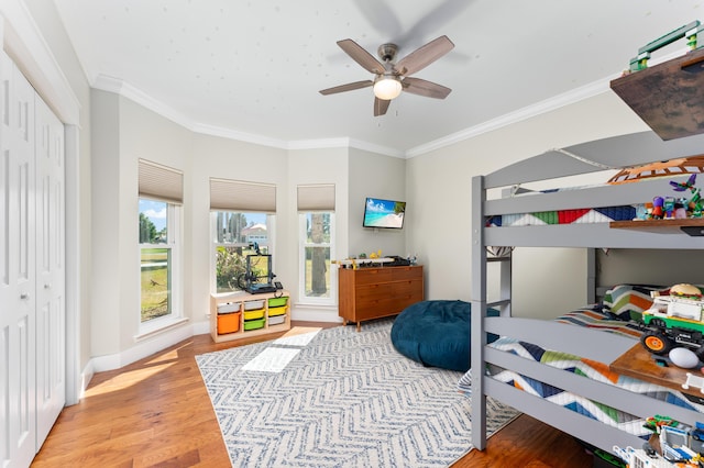 bedroom with baseboards, ceiling fan, wood finished floors, and crown molding