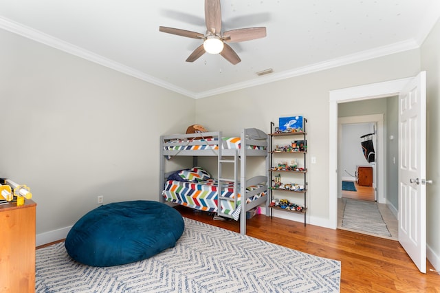 bedroom with baseboards, crown molding, visible vents, and wood finished floors