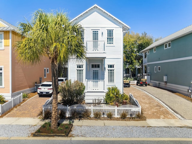 view of front of property featuring a balcony, decorative driveway, and a fenced front yard