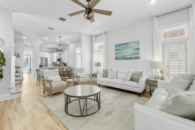 living room featuring recessed lighting, visible vents, light wood-style flooring, and ceiling fan with notable chandelier