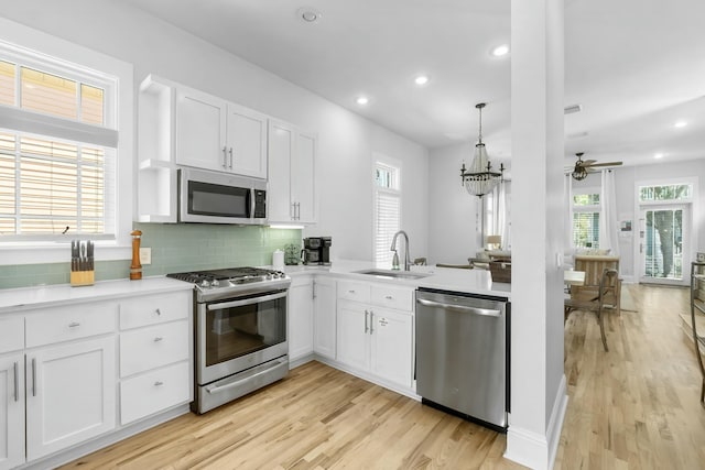 kitchen featuring backsplash, stainless steel appliances, light wood-style floors, white cabinetry, and a sink