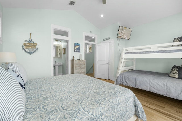 bedroom featuring visible vents, ensuite bath, lofted ceiling, and wood finished floors