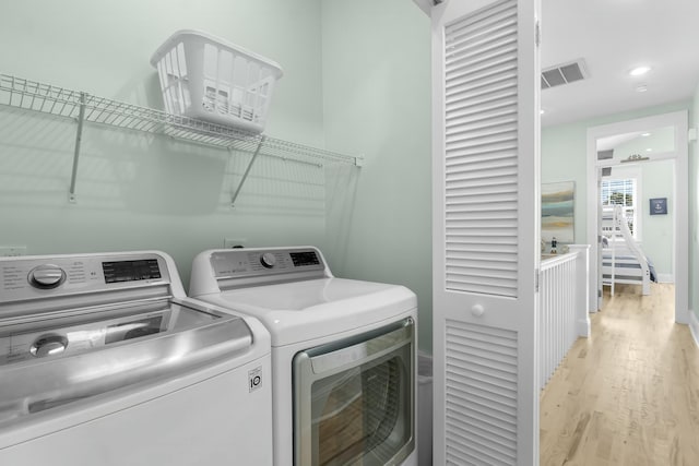 clothes washing area with washing machine and clothes dryer, visible vents, laundry area, recessed lighting, and light wood-style floors