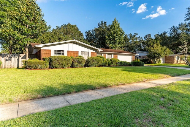 ranch-style house featuring a front yard, fence, board and batten siding, and brick siding