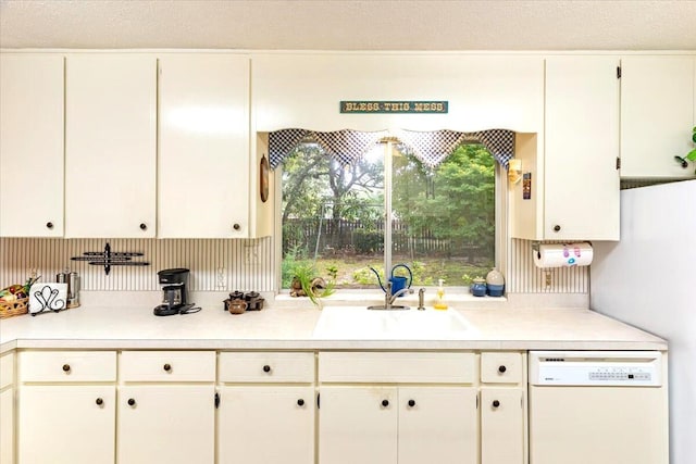 kitchen with a sink, white cabinets, dishwasher, and light countertops