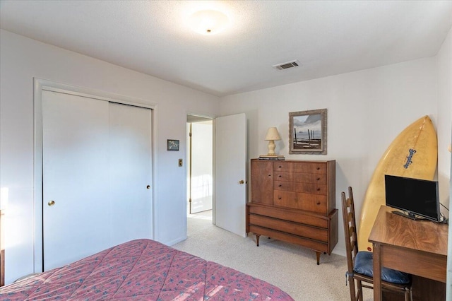 bedroom with a closet, visible vents, and light colored carpet