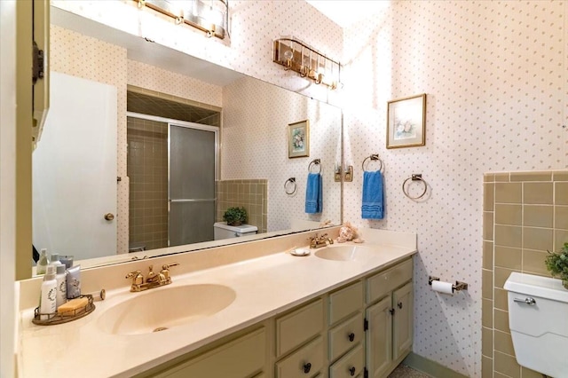 bathroom with a sink, toilet, and wallpapered walls