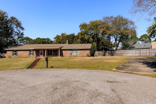 ranch-style home with brick siding, a front yard, and fence