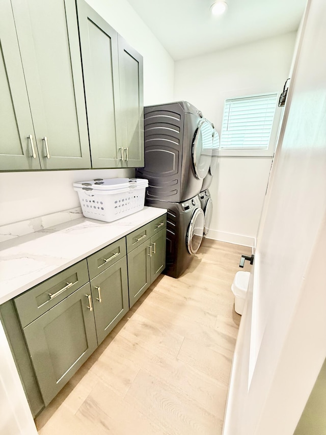 laundry area with baseboards, stacked washing maching and dryer, recessed lighting, cabinet space, and light wood-type flooring