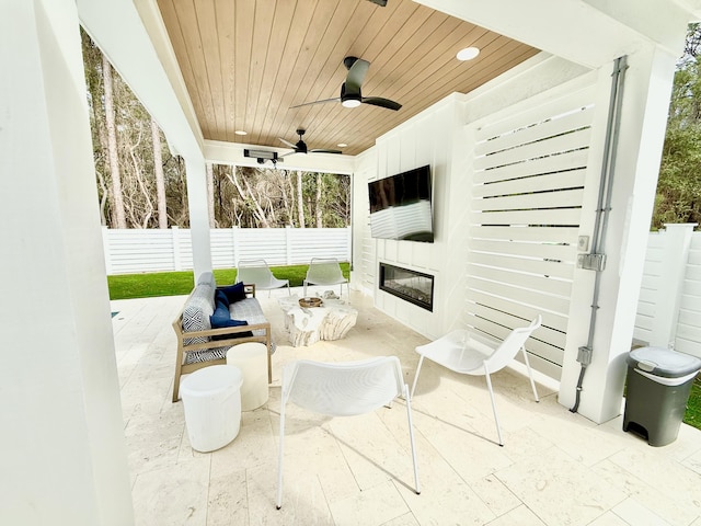 view of patio / terrace featuring an outdoor living space with a fireplace, fence, and ceiling fan