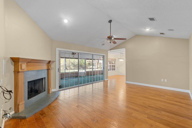 unfurnished living room featuring visible vents, a fireplace with raised hearth, a ceiling fan, light wood-style floors, and vaulted ceiling