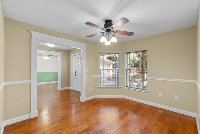 empty room with baseboards, wood-type flooring, and a textured ceiling