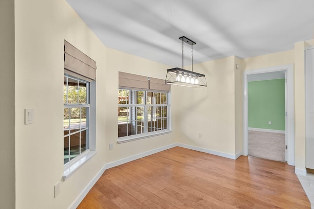 unfurnished dining area featuring baseboards and light wood-style flooring