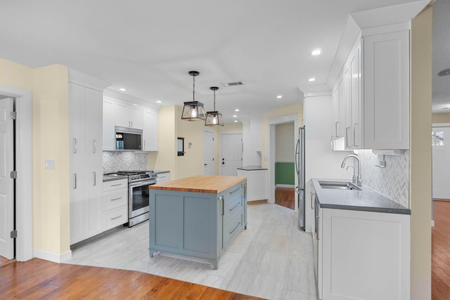 kitchen with visible vents, butcher block counters, a sink, appliances with stainless steel finishes, and a center island