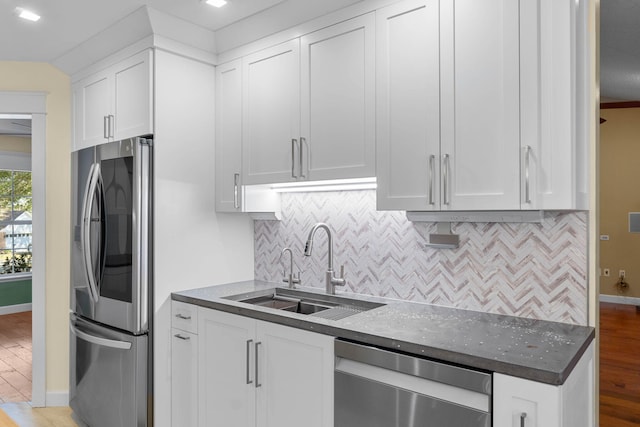 kitchen featuring tasteful backsplash, light wood-style flooring, stainless steel appliances, white cabinetry, and a sink