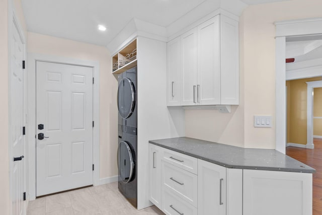 washroom featuring cabinet space and stacked washer and clothes dryer