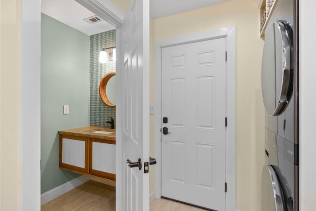 foyer with light wood finished floors, stacked washer / dryer, baseboards, and visible vents