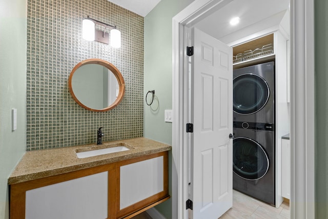 bathroom featuring decorative backsplash, vanity, and stacked washer / dryer