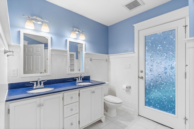 bathroom featuring a sink, a wainscoted wall, toilet, and visible vents