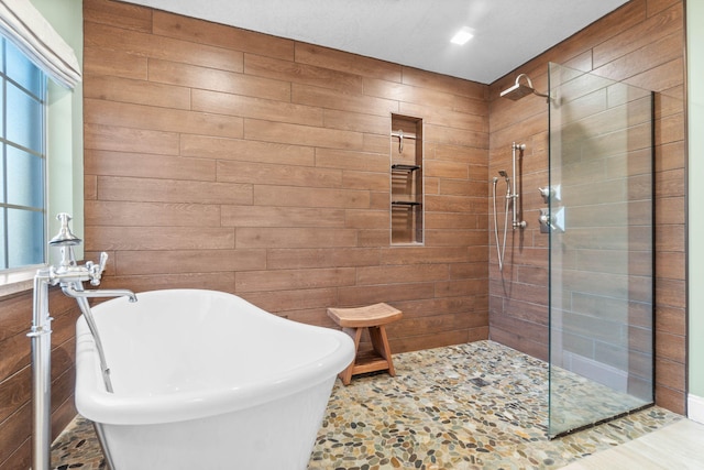 full bath with a soaking tub, wood walls, and walk in shower