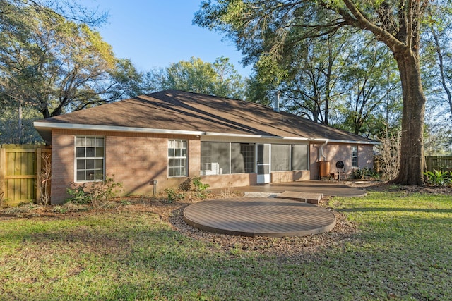 back of property featuring a yard, a sunroom, brick siding, and fence