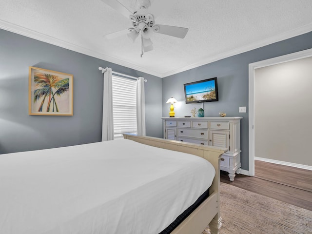 bedroom with ornamental molding, a ceiling fan, a textured ceiling, wood finished floors, and baseboards