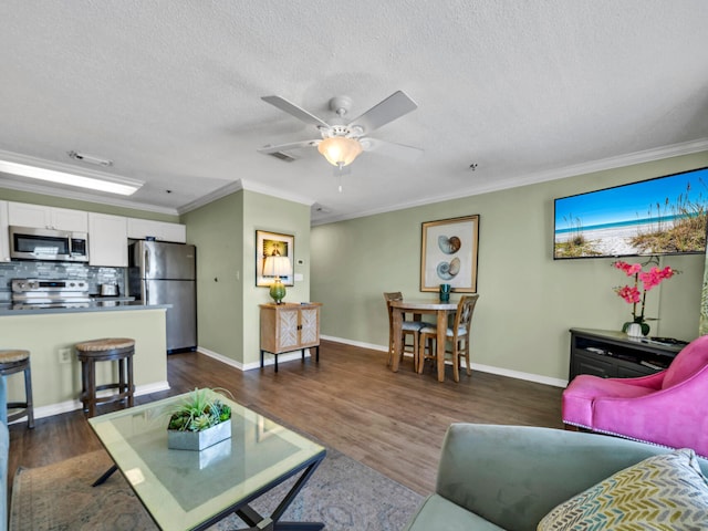 living area with a textured ceiling, dark wood-type flooring, baseboards, and crown molding