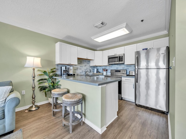 kitchen with appliances with stainless steel finishes, visible vents, light wood-style flooring, and white cabinetry