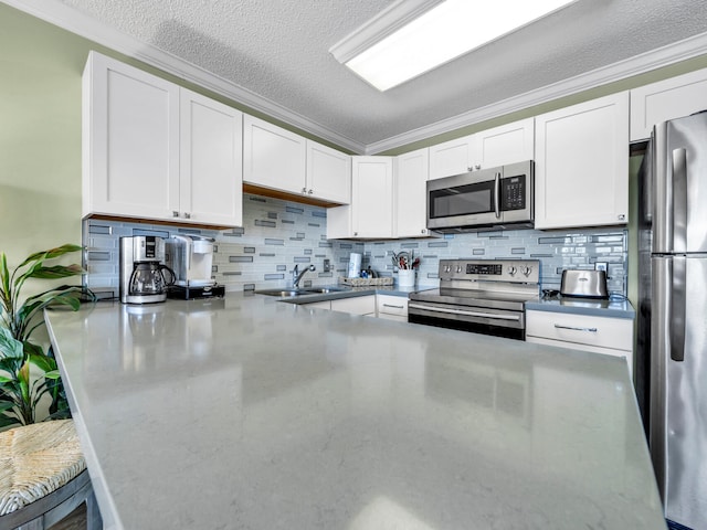 kitchen featuring ornamental molding, appliances with stainless steel finishes, a sink, and white cabinets