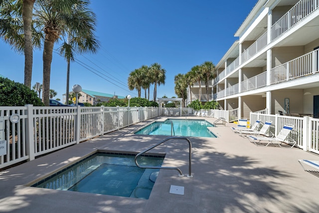 community pool featuring a community hot tub, fence, and a patio