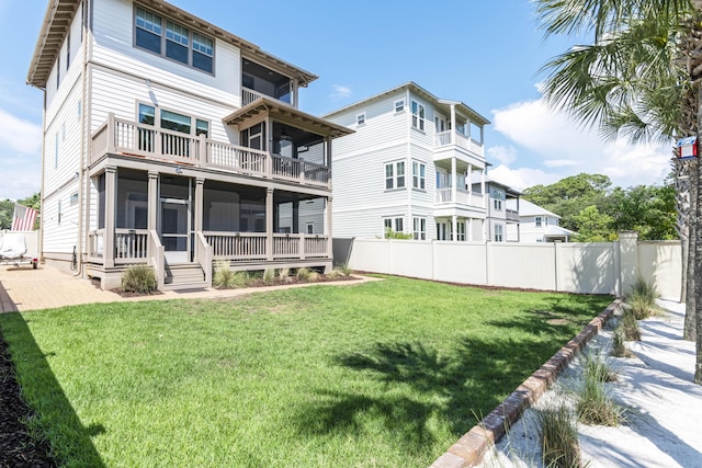 back of property featuring a lawn, fence, a balcony, and a sunroom