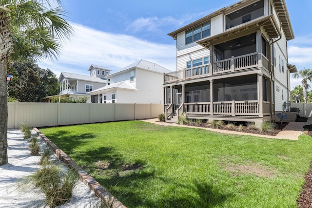 back of house featuring a balcony, a lawn, a fenced backyard, and a sunroom